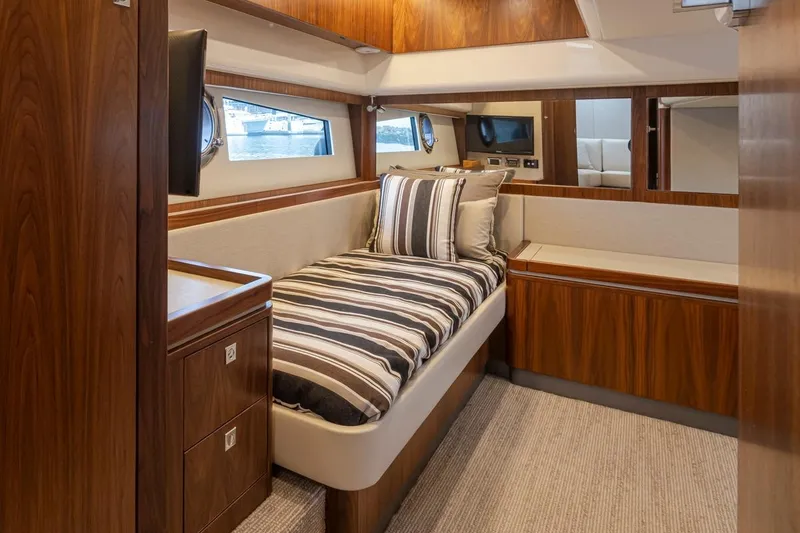 Slide: The Image of Luxurious cabin interior of 2018 Riviera 4800 Sport Yacht with wood finish and striped bedding. - 27