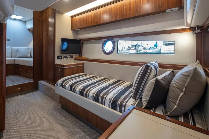 Slide: The Image of Luxurious interior of 2018 Riviera 4800 Sport Yacht with striped bedding and wood accents. - 31