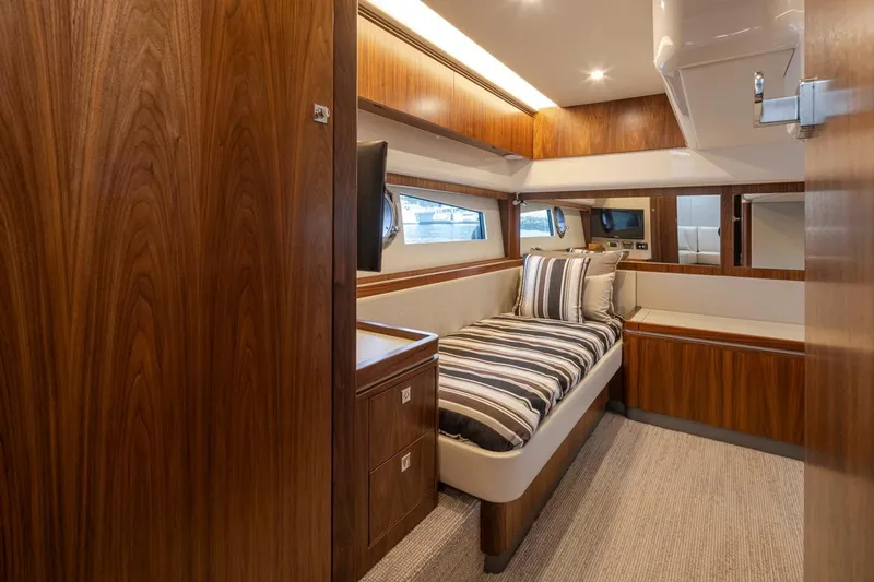 Slide: The Image of Luxurious 2018 Riviera 4800 Sport Yacht cabin with wood finish and striped bedding. - 34