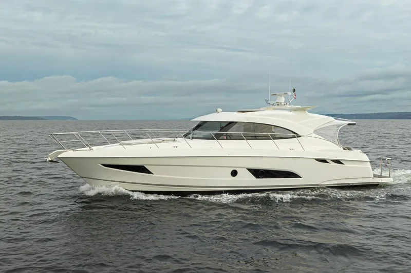 Slide: The Image of 2018 Riviera 4800 Sport Yacht cruising on open water under cloudy skies. - 4