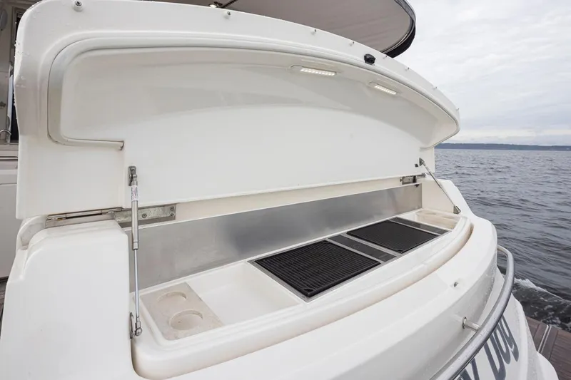 Slide: The Image of 2018 Riviera 4800 Sport Yacht with open rear storage compartment by the sea. - 48