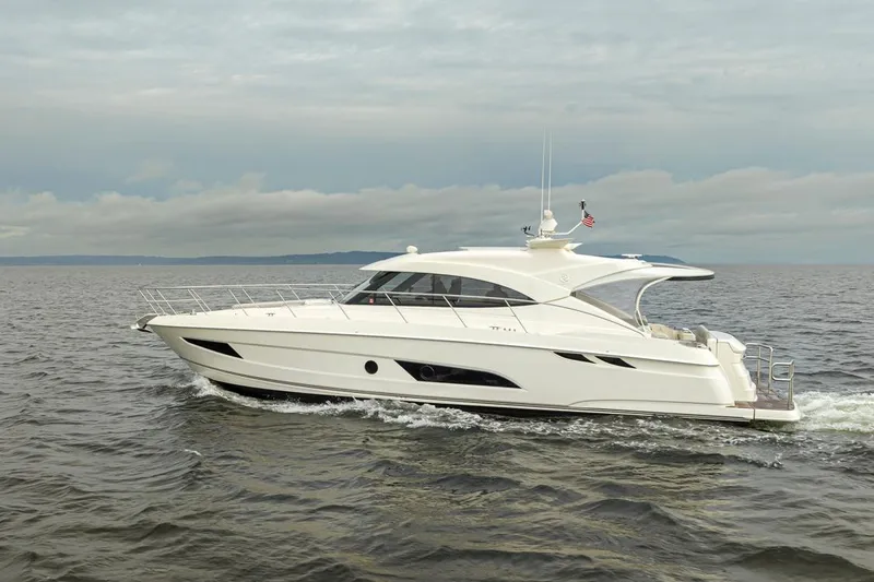 Slide: The Image of 2018 Riviera 4800 Sport Yacht cruising on open water under cloudy skies. - 7