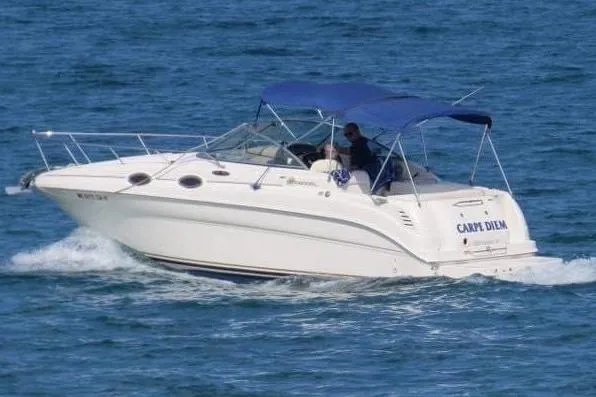 The Image of 2003 Sea Ray 260 Sundancer boat cruising on open water with blue canopy. - 0
