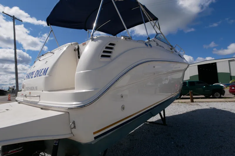 Slide: The Image of 2003 Sea Ray 260 Sundancer boat with blue canopy, docked under a clear sky. - 11