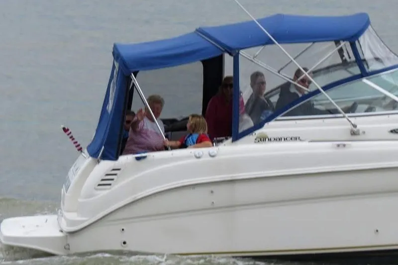 Slide: The Image of 2003 Sea Ray 260 Sundancer boat with blue canopy cruising on water. - 2