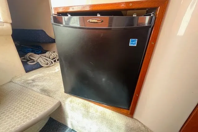 Slide: The Image of Compact fridge inside 2003 Sea Ray 260 Sundancer boat cabin, with ropes nearby. - 34