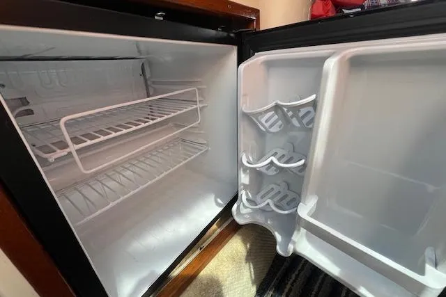 Slide: The Image of Open refrigerator inside a 2003 Sea Ray 260 Sundancer boat, showing empty shelves and door storage. - 35