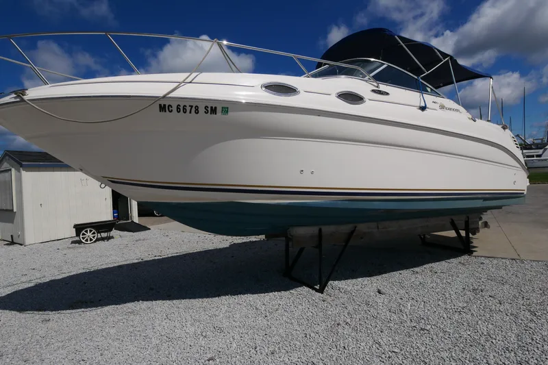 Slide: The Image of 2003 Sea Ray 260 Sundancer boat on display, white hull, blue canopy, sunny day. - 6