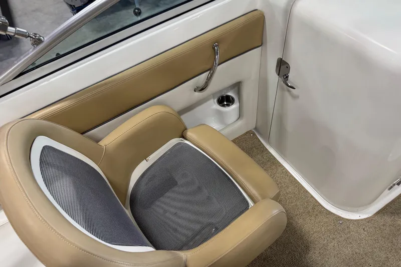 Slide: The Image of 2011 Sea Ray 240 Sundeck interior with tan and gray seating, cup holder, and door. - 10