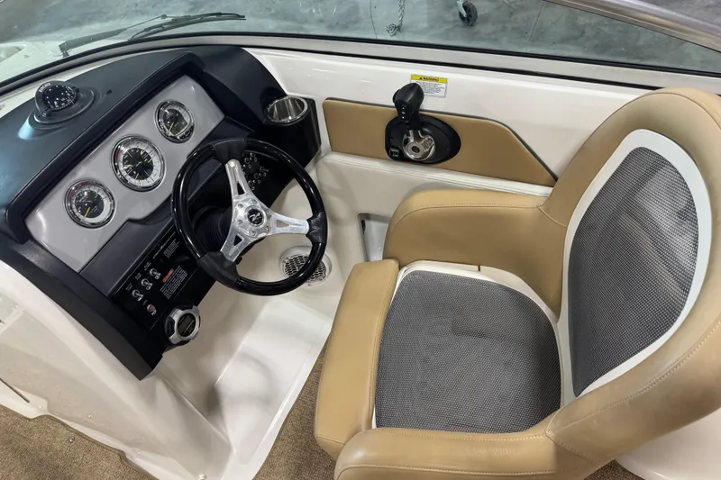 Slide: The Image of 2011 Sea Ray 240 Sundeck helm with steering wheel, gauges, and beige captain's chair. - 11