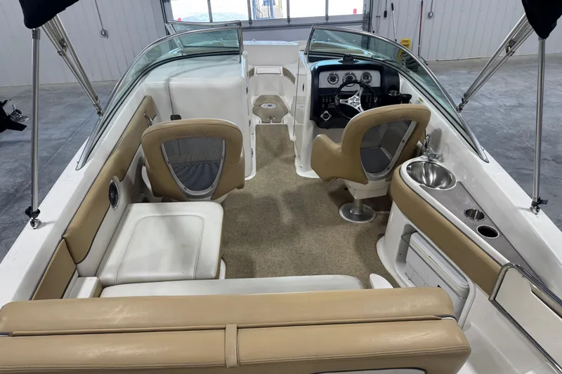 Slide: The Image of 2011 Sea Ray 240 Sundeck interior with beige seating, steering console, and sink. - 8