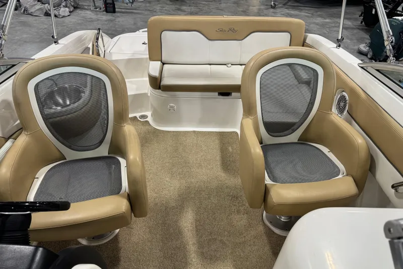 Slide: The Image of 2011 Sea Ray 240 Sundeck interior with beige seating and carpeted floor. - 9