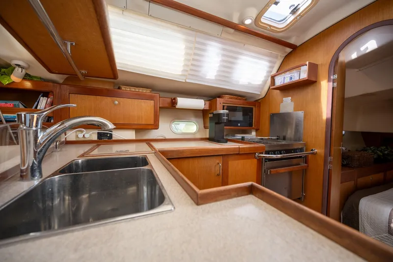 Slide: The Image of 1999 Hunter 410 yacht kitchen with modern amenities and wooden cabinetry. - 21
