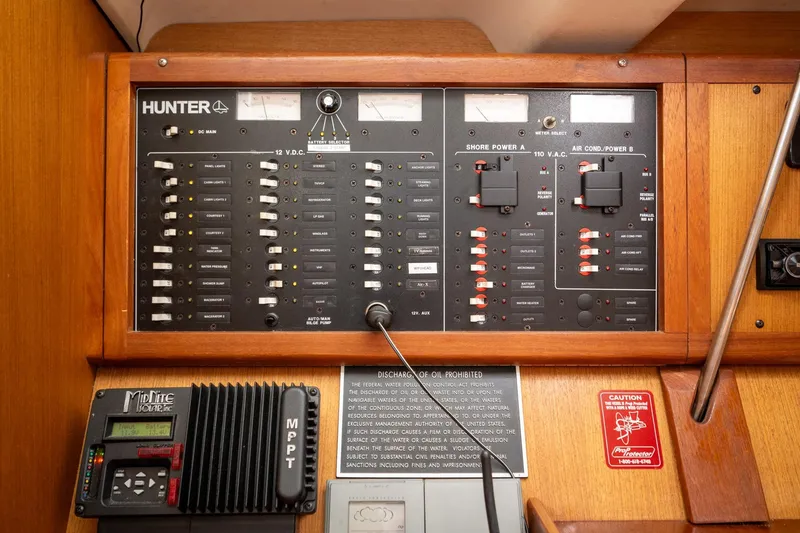 Slide: The Image of Electrical control panel on a 1999 Hunter 410 sailboat, featuring various switches and meters. - 23