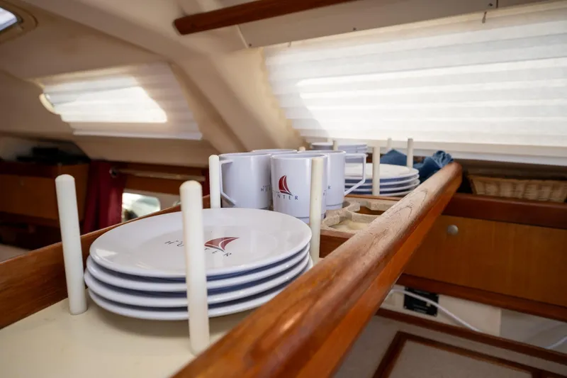 Slide: The Image of Interior of 1999 Hunter 410 yacht with branded plates and mugs in wooden rack. - 26