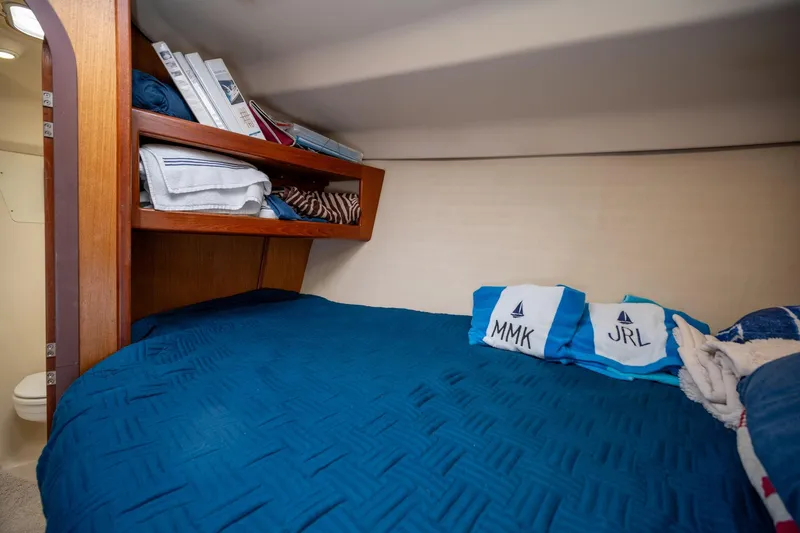 Slide: The Image of Cozy cabin interior of 1999 Hunter 410 sailboat with blue bedding and wooden shelves. - 29