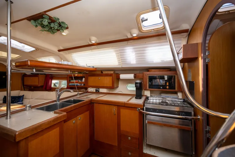 Slide: The Image of Interior of 1999 Hunter 410 sailboat kitchen with wood cabinetry and modern appliances. - 5