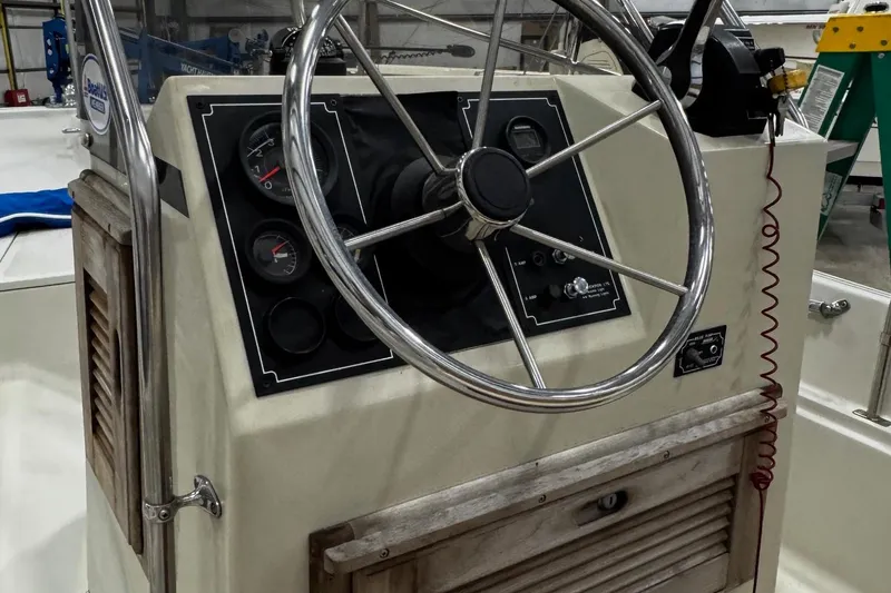 Slide: The Image of 1991 Boston Whaler 17 Montauk steering console with gauges and controls in a boatyard. - 13