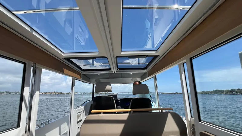 Slide: The Image of Interior view of 2025 Nimbus Commuter 11 boat with panoramic windows and scenic water backdrop. - 21
