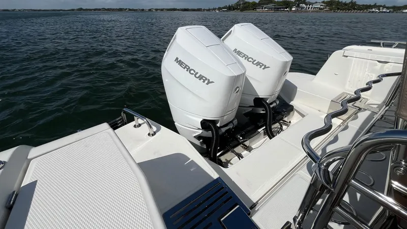 Slide: The Image of Twin Mercury outboard engines on a 2025 Nimbus Commuter 11 boat, docked on calm water. - 8