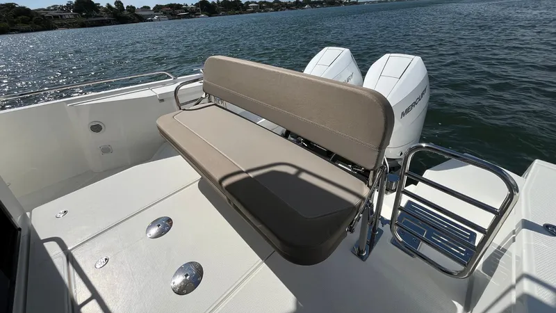 Slide: The Image of 2025 Nimbus Commuter 11 boat with cushioned seating and dual outboard motors on a sunny day. - 13