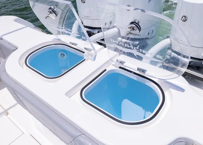 Slide: The Image of Livewell compartments on 2025 Invincible 43 Open Fisherman boat, featuring clear lids and blue interiors. - 33