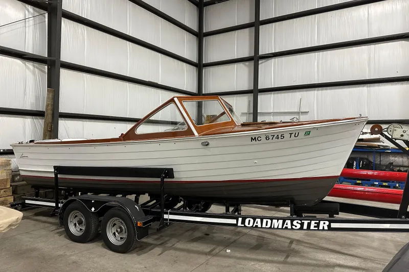 The Image of 1961 Lyman 21 Runabout boat on Loadmaster trailer in indoor storage facility. - 0