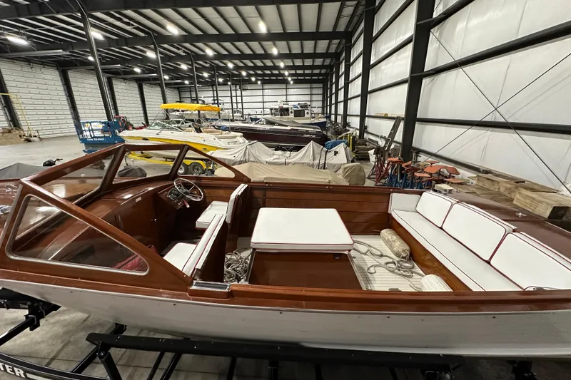 Slide: The Image of 1961 Lyman 21 Runabout boat in a storage facility, showcasing classic wooden design. - 10