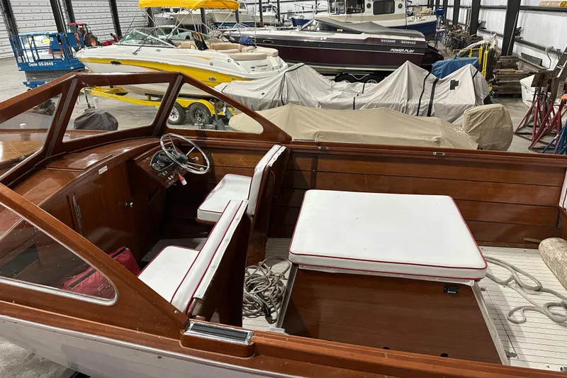 Slide: The Image of 1961 Lyman 21 Runabout boat interior with wooden finish and white seating in a storage facility. - 7