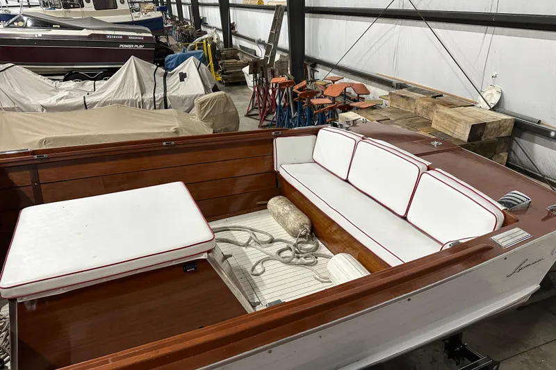 Slide: The Image of 1961 Lyman 21 Runabout boat interior with white and red cushioned seating in a storage facility. - 8