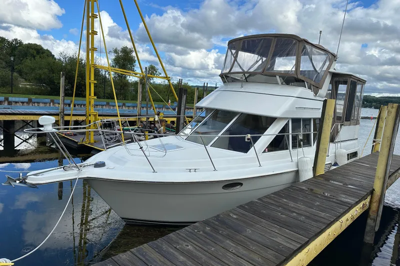 Slide: The Image of 1997 Carver 325 Motor Yacht docked at a marina under a partly cloudy sky. - 4
