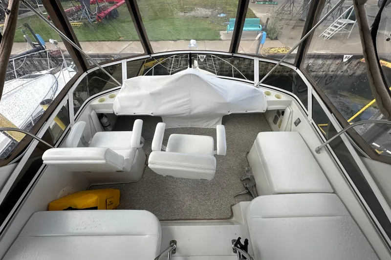 Slide: The Image of 1997 Carver 325 Motor Yacht interior with white seating and helm, docked at marina. - 12