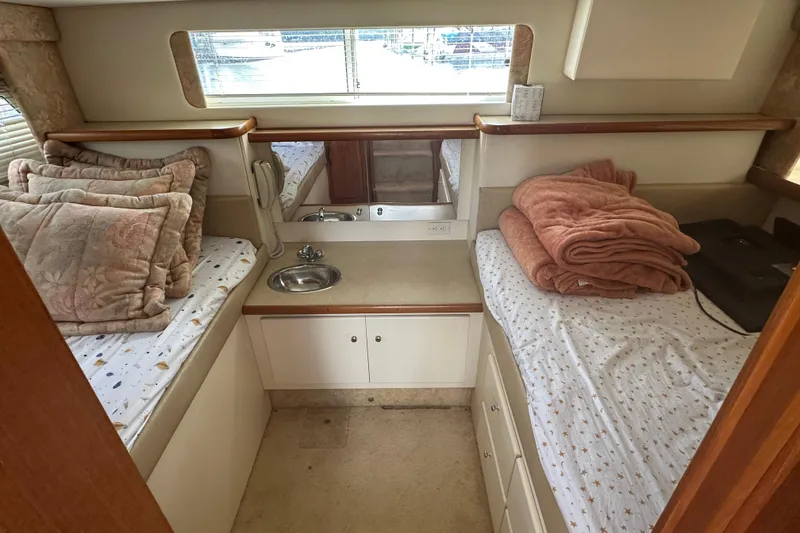 Slide: The Image of 1997 Carver 325 Motor Yacht cabin with twin beds, pillows, and a small sink. - 32