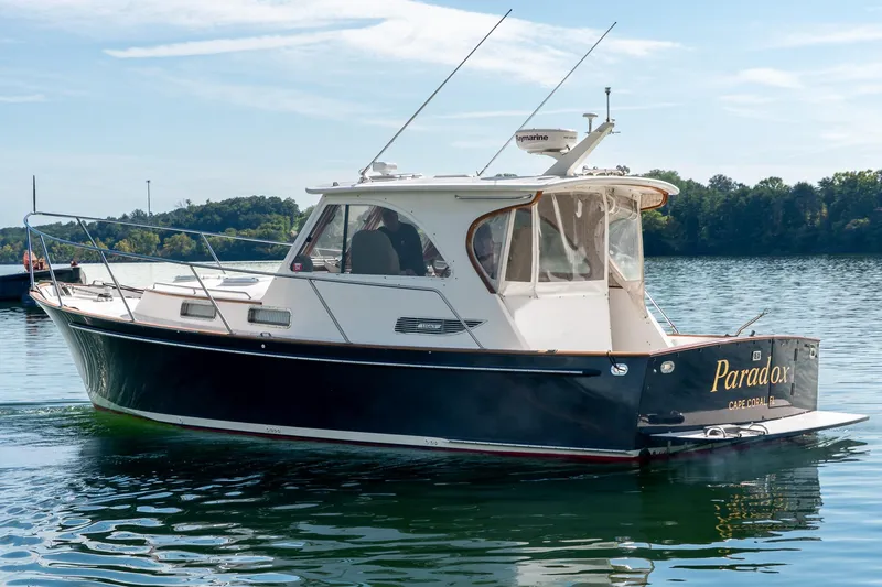 Slide: The Image of 2002 Legacy 34 Express boat named "Paradox" on a calm lake. - 2