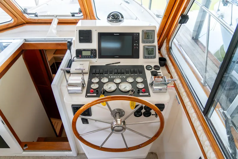 Slide: The Image of Helm station of 2002 Legacy 34 Express boat with navigation instruments and wooden steering wheel. - 28