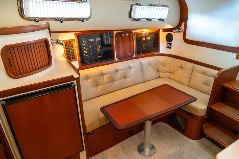 Slide: The Image of 2002 Legacy 34 Express yacht interior with beige leather seating and wooden table. - 33