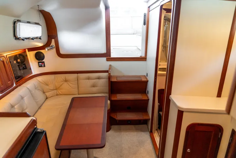 Slide: The Image of 2002 Legacy 34 Express boat interior with beige seating and wooden table. - 34