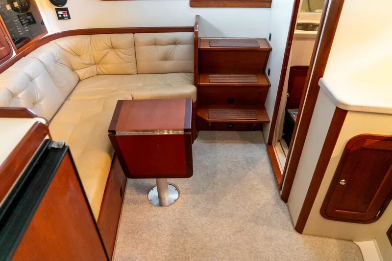 Slide: The Image of 2002 Legacy 34 Express boat interior with beige leather seating and wooden table. - 35