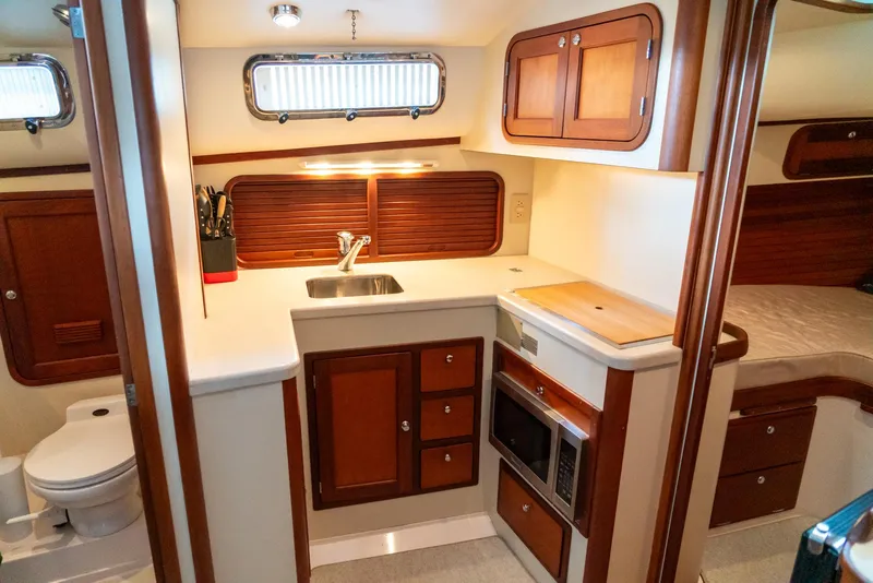Slide: The Image of 2002 Legacy 34 Express yacht interior kitchen with sink, microwave, and wooden cabinets. - 36