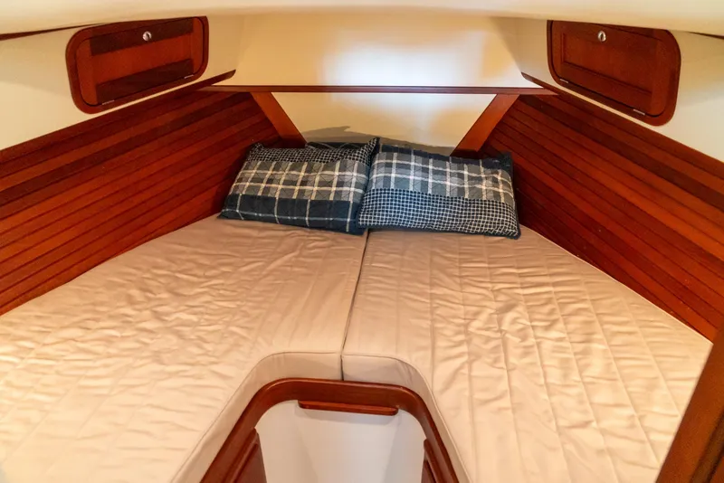 Slide: The Image of 2002 Legacy 34 Express boat cabin with cozy bedding and wooden interior. - 39