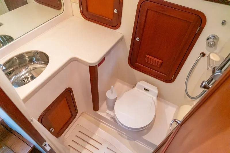 Slide: The Image of Compact bathroom in 2002 Legacy 34 Express boat with sink, toilet, and wooden cabinets. - 42