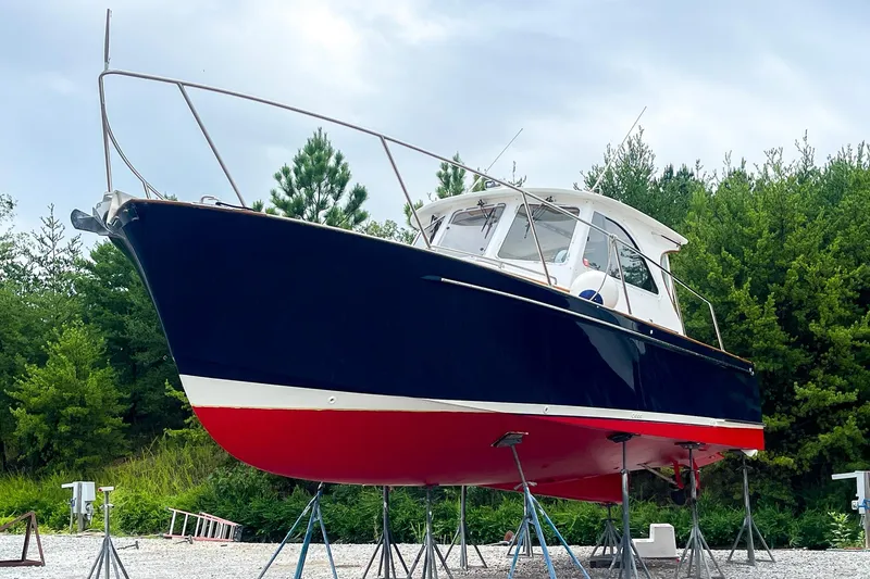 Slide: The Image of 2002 Legacy 34 Express boat on stands, blue hull, red bottom, surrounded by trees. - 5