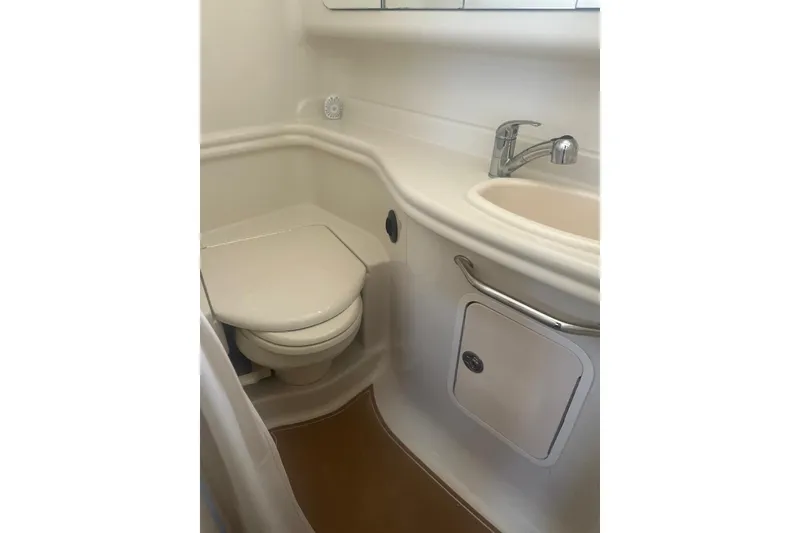 Slide: The Image of 2006 Sea Ray 340 Sundancer bathroom with toilet, sink, and storage cabinet. - 23