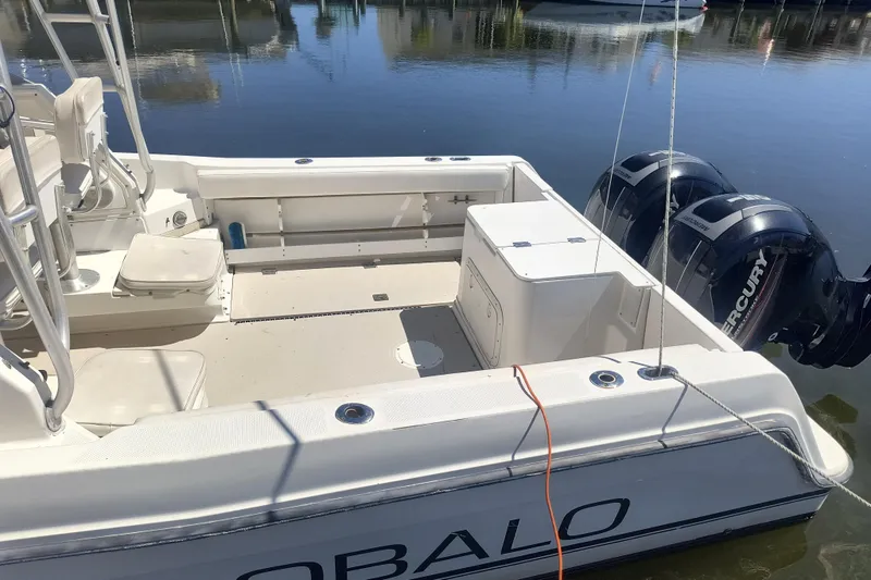 Slide: The Image of 1995 Robalo 2440 Walkaround boat with dual Mercury outboard engines, docked on calm water. - 4