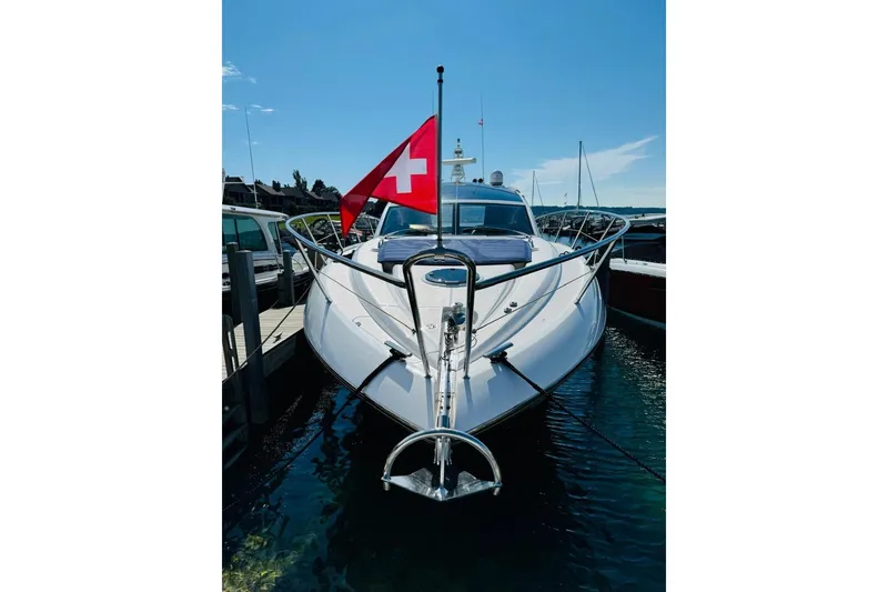 Slide: The Image of 2012 Sunseeker Portofino 48 yacht docked, displaying a Swiss flag under clear blue skies. - 2