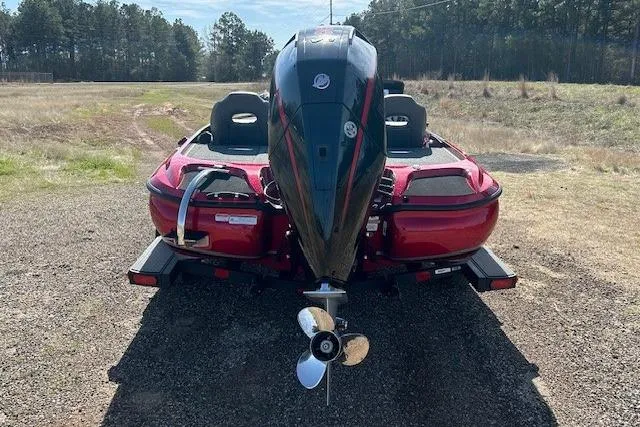 Slide: The Image of Red 2025 Nitro Z19 boat with powerful outboard motor, parked on gravel near trees. - 7