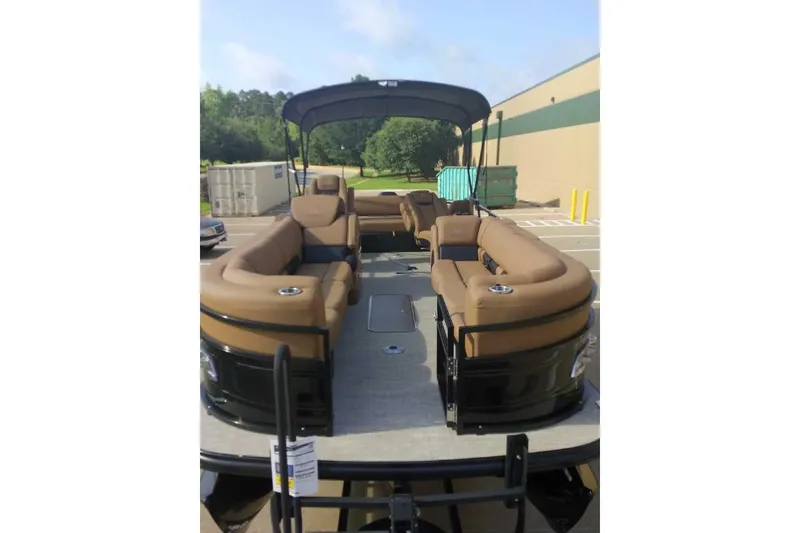 Slide: The Image of 2025 Regency 250 LE3 Sport pontoon boat with tan seating and canopy in parking lot. - 8