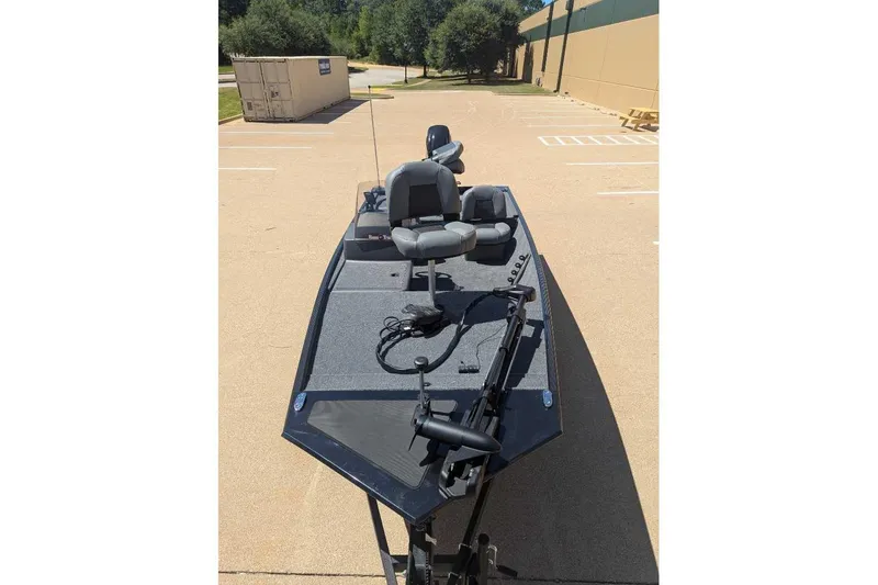 Slide: The Image of 2025 Tracker Bass Tracker Classic XL boat parked outdoors, featuring seating and fishing equipment. - 15