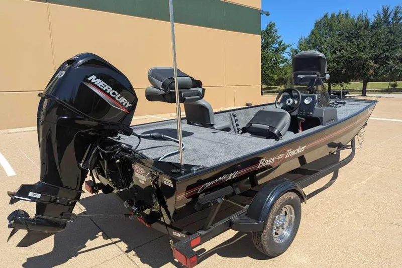 Slide: The Image of 2025 Tracker Bass Tracker Classic XL boat with Mercury engine, parked outdoors. - 2