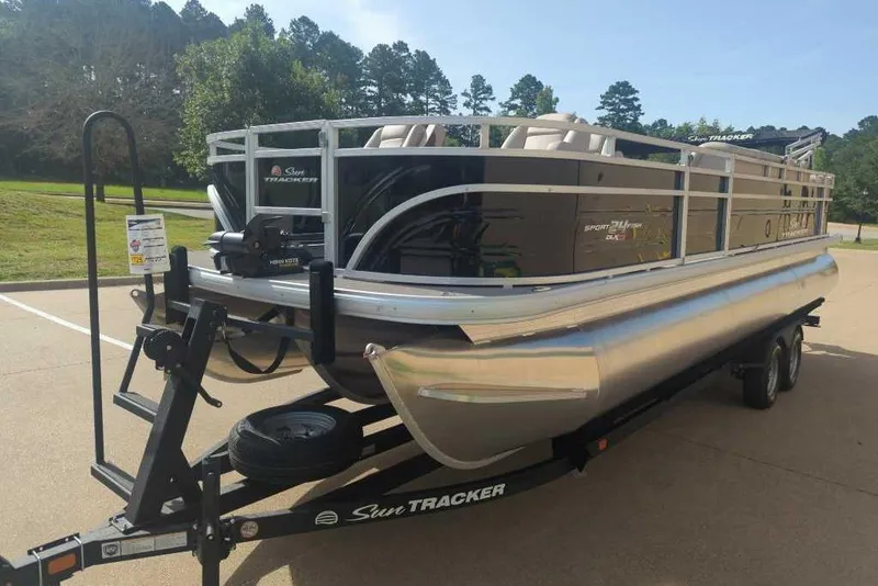 Slide: The Image of 2025 Sun Tracker Sportfish 24 XP3 pontoon boat on a trailer in a sunny parking lot. - 15